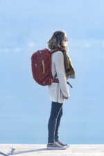 Une femme contemple le lac Annecy avec le sac de voyage Neo Sambuy Nomad sur son dos